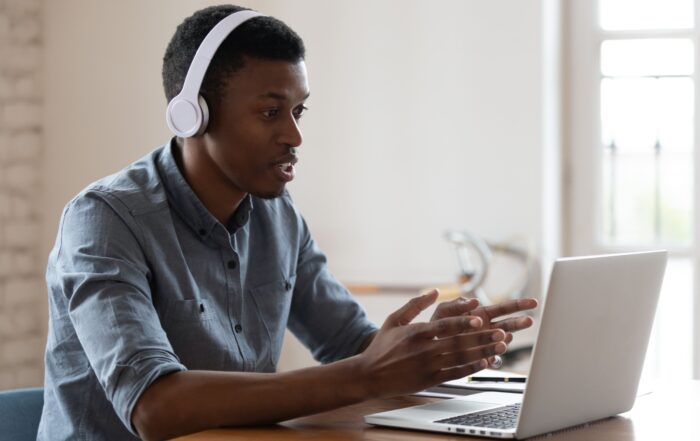 businessman wearing wireless headphones makes conference video call talk looks at pc screen,