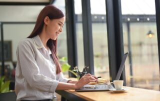 woman sitting in modern coffee shop and working online with computer laptop