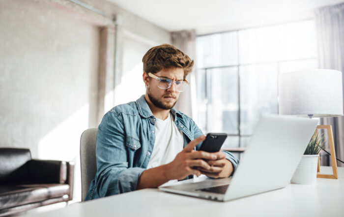 Young man with smartphone in his hands. Modern businessman at sunny office.