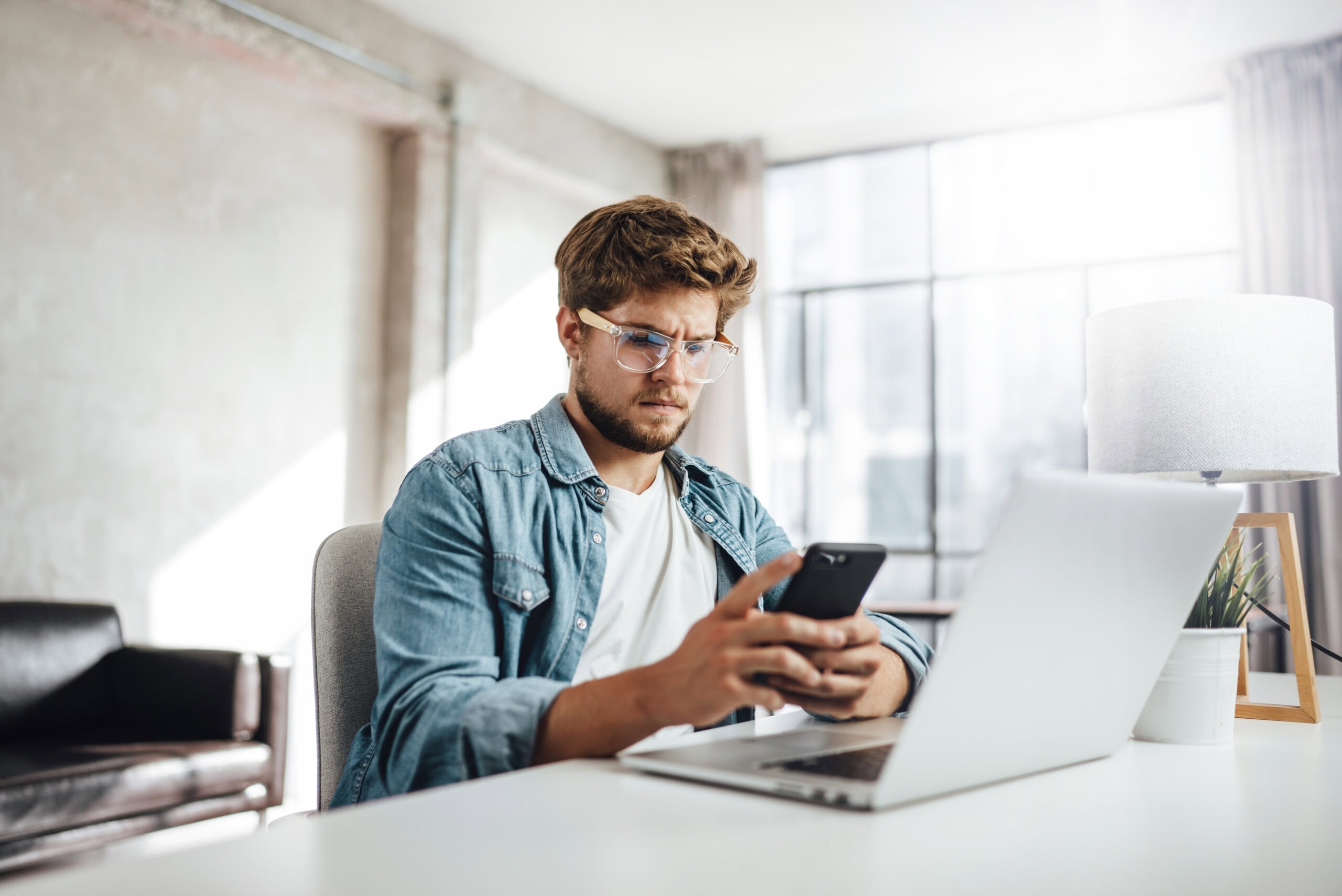 Young man with smartphone in his hands. Modern businessman at sunny office.