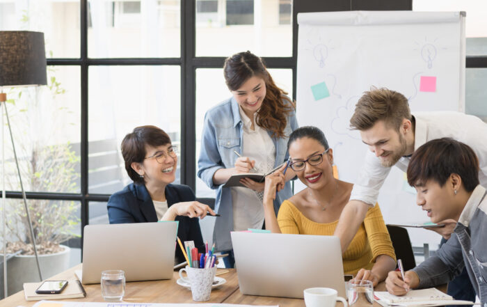 group of happy business people working together, meeting and brainstorming in office. Use computer, laptop, tablet, mobile phone.